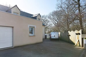 A residential driveway with a garage, a white van parked, and a wooden fence.