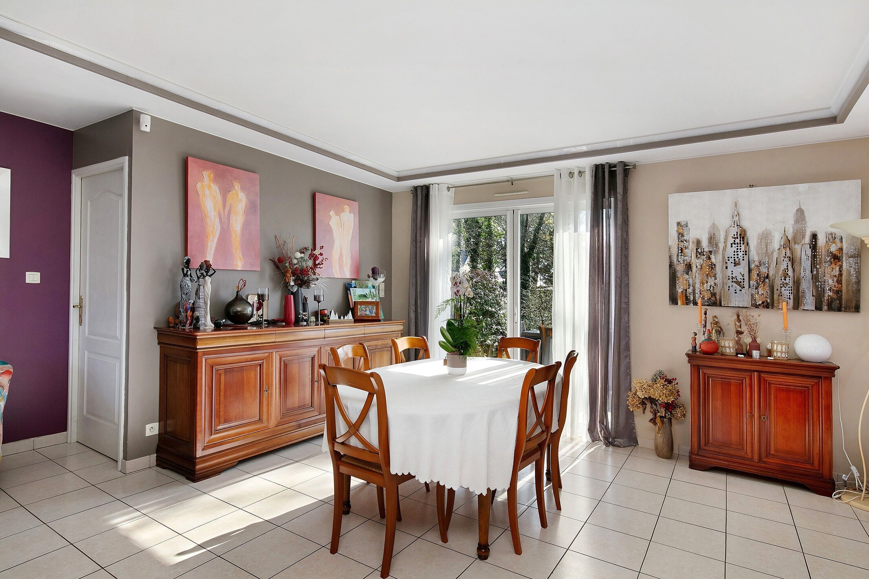A dining area with a table, chairs, a cabinet, and artwork on the walls.