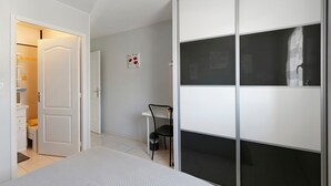 Un dormitorio con cama, armario, escritorio y silla.
