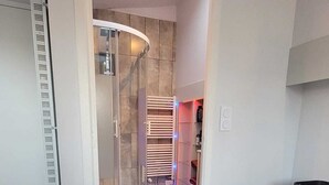 Une chambre d’hôtel avec un lit, un espace douche et un plancher en bois.