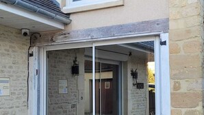 Une entrée d’immeuble avec une porte en verre, des murs en pierre et une fenêtre au-dessus de la porte.
