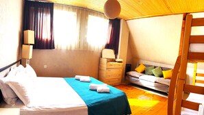 A bedroom with a bed, a dresser, a bench, and a hanging light fixture. - Cozy Corner (Borjomi)