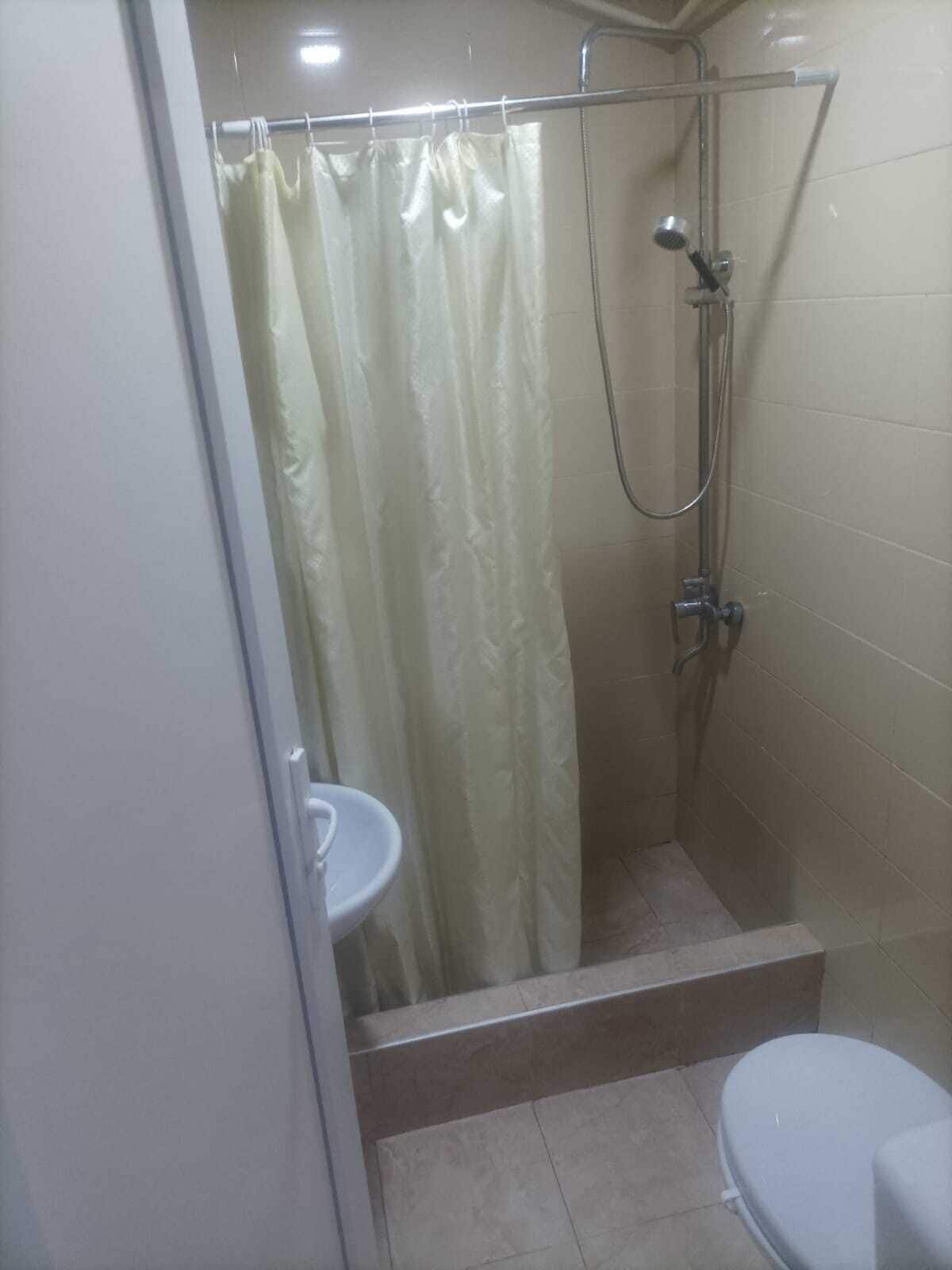 Un petit espace de douche fermé, comprenant une pomme de douche, des toilettes et un lavabo.