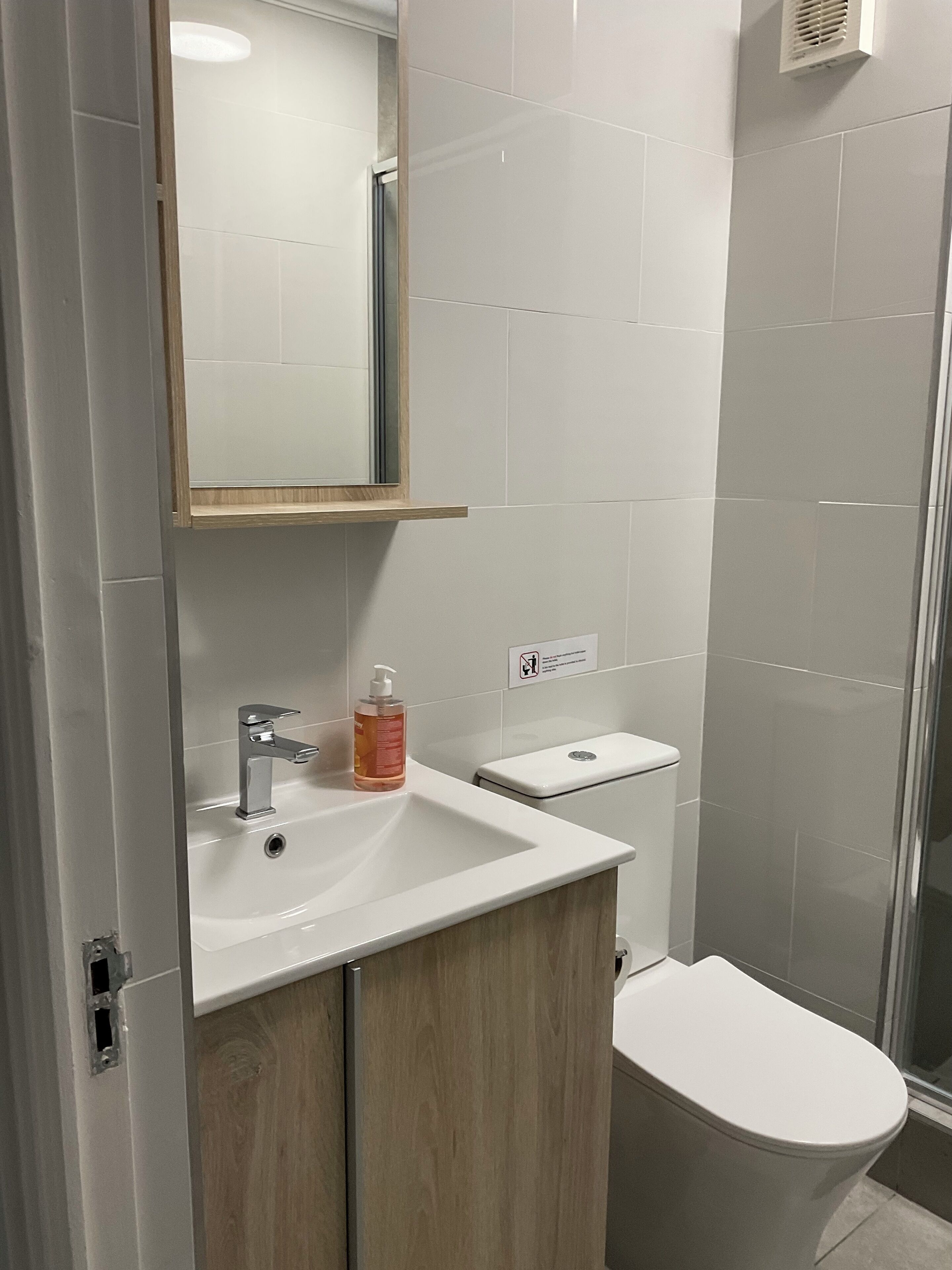 A modern bathroom with a white sink, mirror, and toilet.
