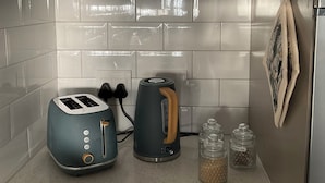 Eine Küche mit Kaffeemaschine, Toaster, Wasserkocher und Teedosen.
