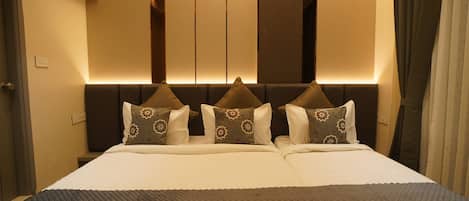 Een hotelkamer met een groot bed, twee nachtkastjes en een hoofdbord met ingebouwde verlichting.
