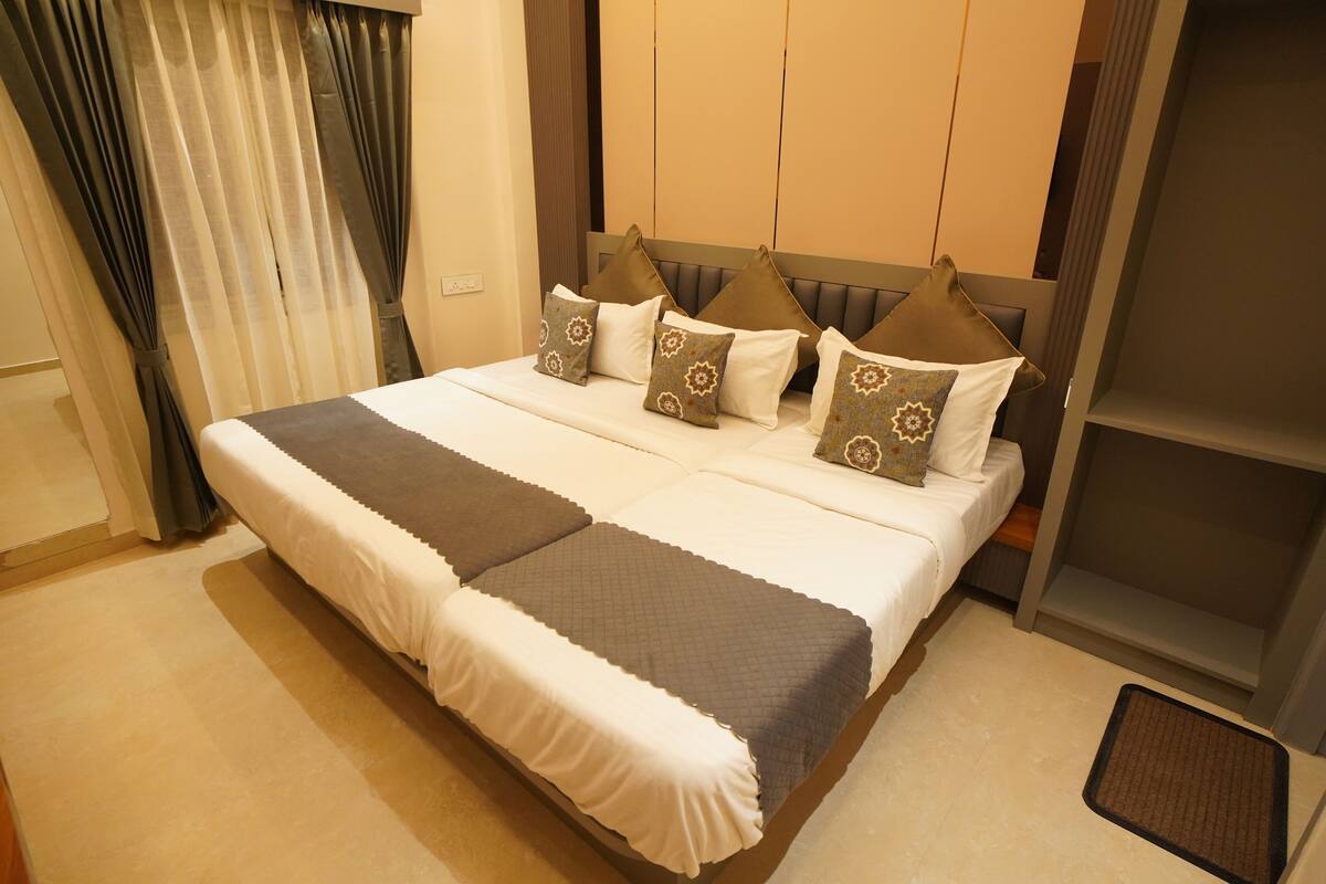 A neatly made bed with a white and gray bedspread, multiple pillows with patterned designs, and a headboard with vertical panels.