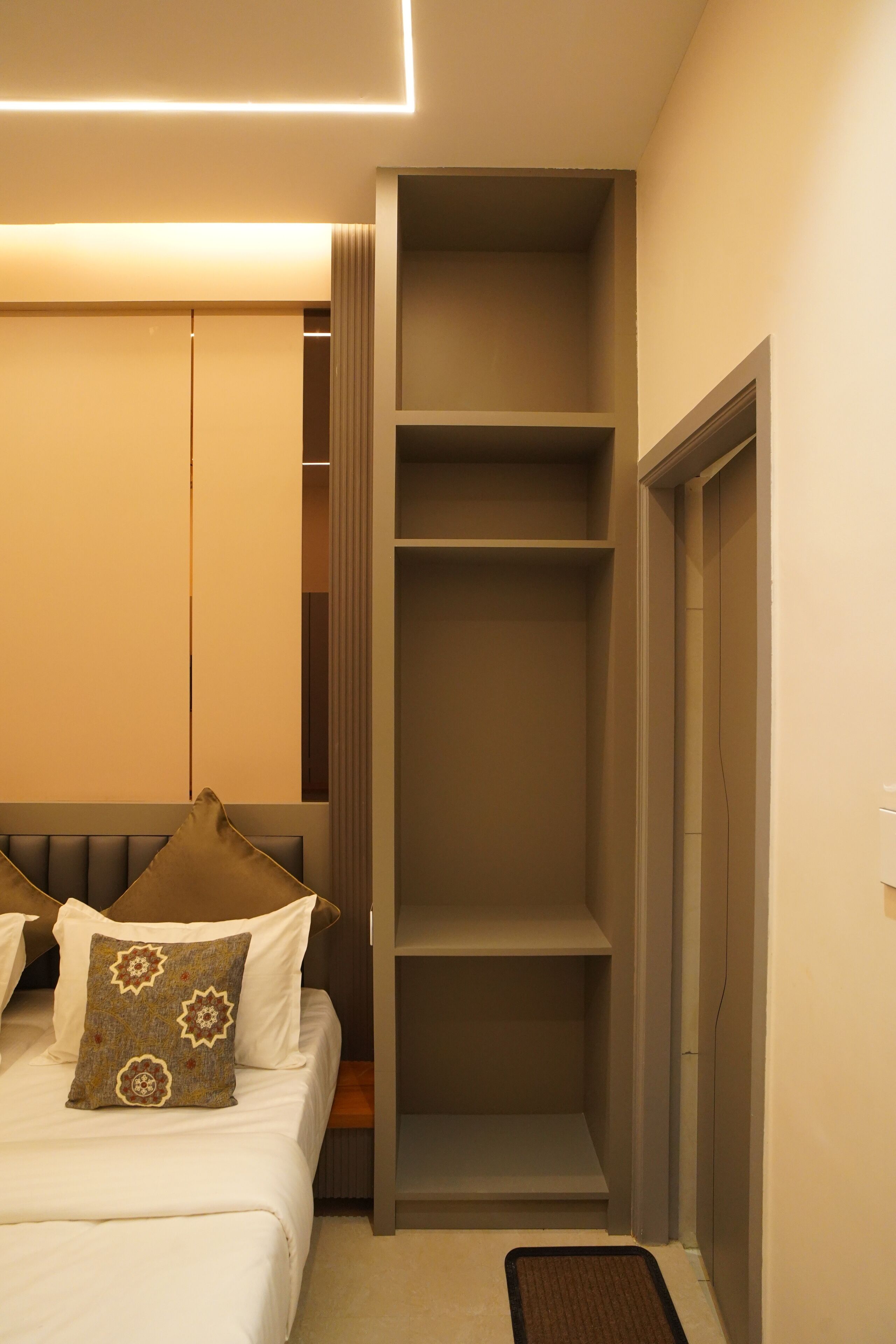 A bedroom with a bed, a bedside table, a wardrobe, and a built-in shelving unit.
