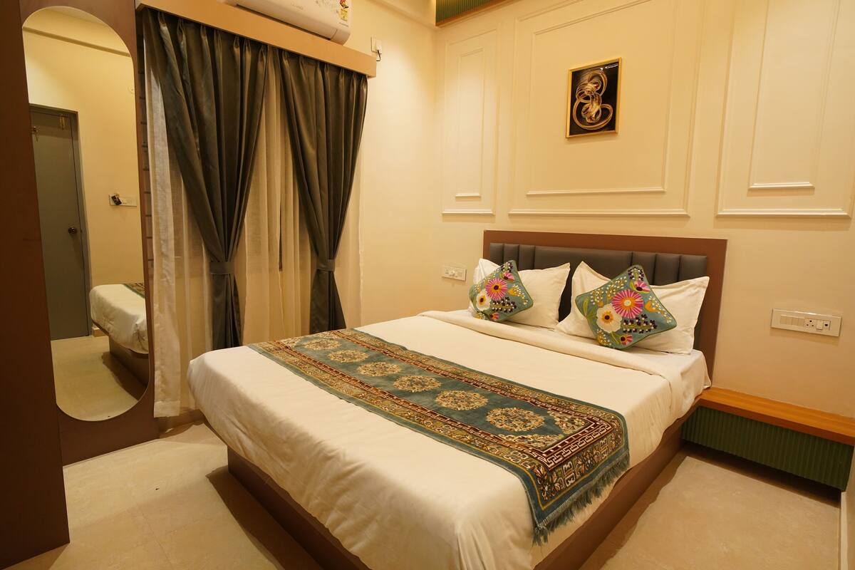 A hotel room with a bed, a bathroom, and a wall-mounted air conditioner.