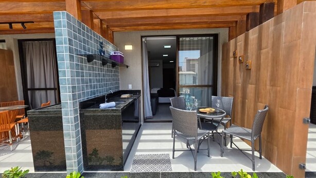 Un patio con una parrilla, asientos al aire libre y vista hacia la casa.