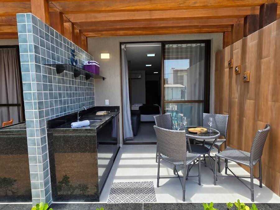 A patio area with a grill, outdoor seating, and a view into the house.