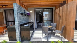 A patio area with a kitchen counter, chairs, and a small table. - Acqua Beach Flat Tamandare by la Playa (Tamandaré)