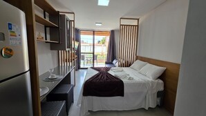 Habitación de hotel compacta con cama, escritorio pequeño, refrigerador y vistas al exterior.
