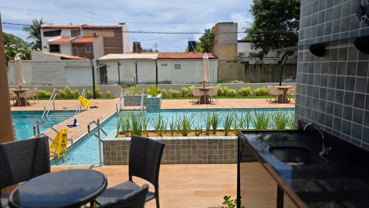 A rooftop pool area with a view of the city, including buildings and trees.