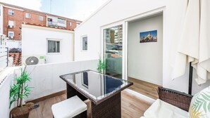 A balcony with a glass table, wicker furniture, and a potted plant.