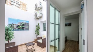 A modern apartment with a balcony, a dining area, and a living room with a large window.