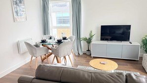 Ett modernt vardagsrum med en matplats, en soffa, en tv och en krukväxt.
