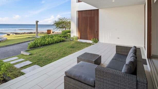 Eine moderne Terrassenanlage mit einer Sitzecke und Blick auf den Ozean.