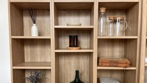 A wooden shelving unit with various items including a vase, a bottle, and books. - Charming Aguçadoura House, 2 Min to Beach • Garden & Pet-Friendly (Aguçadoura)