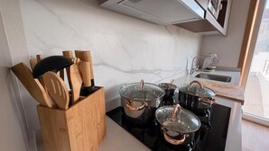 A kitchen with a black stove, wooden utensil holder, and pots on the counter. - Charming Aguçadoura House, 2 Min to Beach • Garden & Pet-Friendly (Aguçadoura)