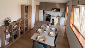 A modern kitchen with built-in appliances and a dining area with a table set for four. - Charming Aguçadoura House, 2 Min to Beach • Garden & Pet-Friendly (Aguçadoura)