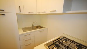 A kitchen with white cabinets, a stainless steel sink, and a gas stove. - Apartment 50mt From the Beach (Lignano Sabbiadoro)