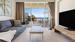 A modern living room with a sofa, a coffee table, a TV, and a balcony with a view of the sea. - Casa Marta - Seaviews (Torremolinos)