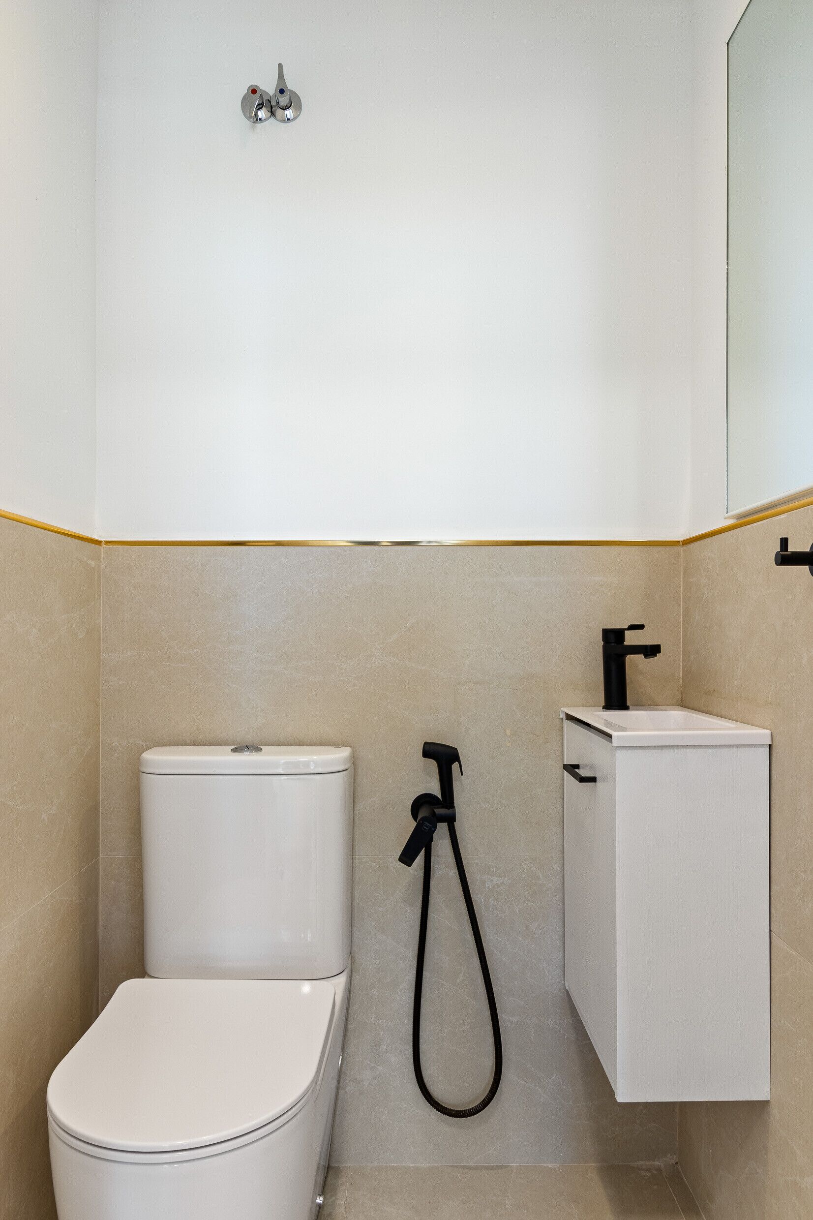 Et badeværelse med toilet, bruser og håndvask.