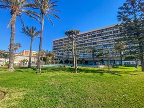 A multi-story hotel with a pool and lush green lawn. - Casa Marta - Seaviews (Torremolinos)
