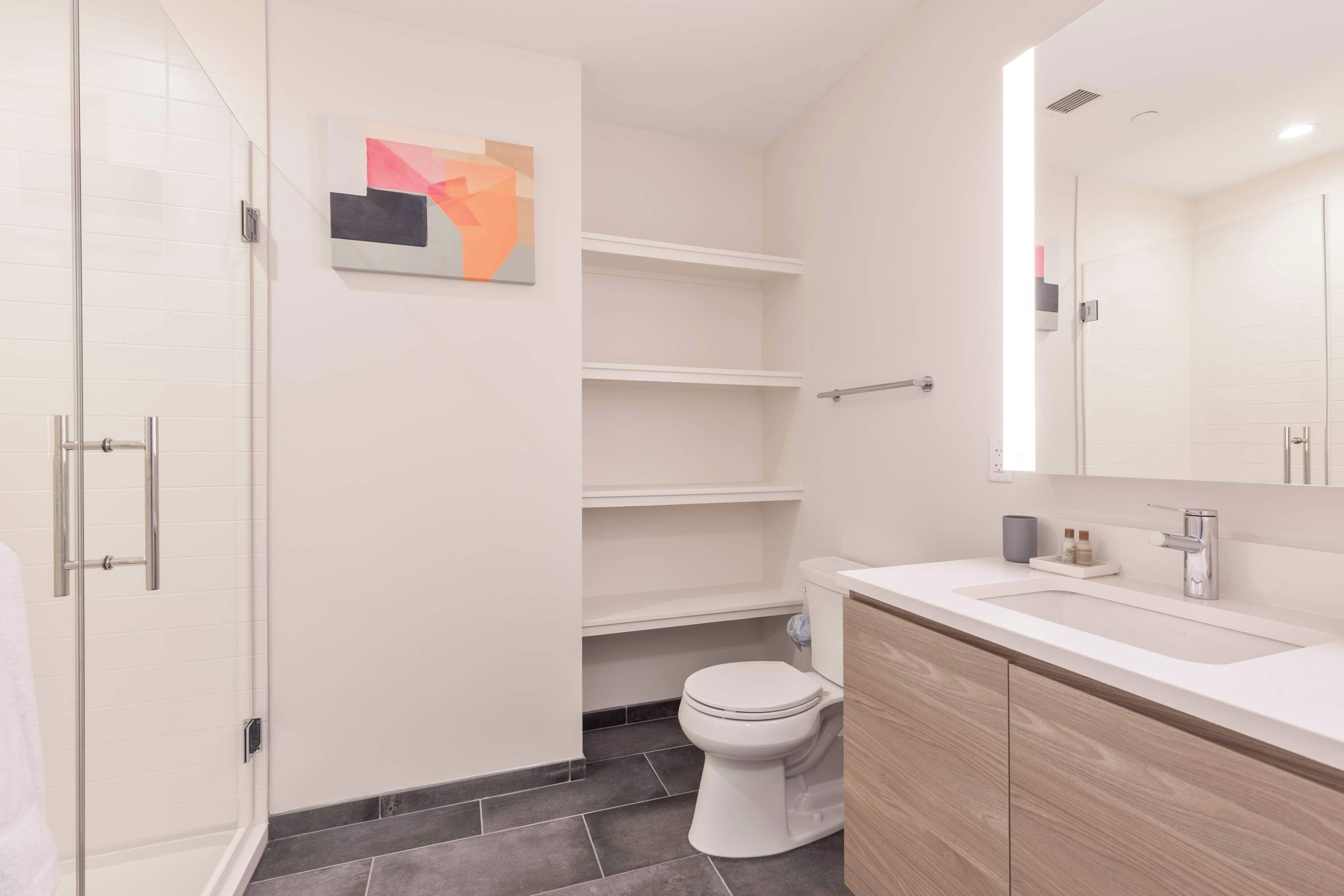Une salle de bain moderne avec une douche à parois de verre, des toilettes et un meuble-lavabo avec un miroir.