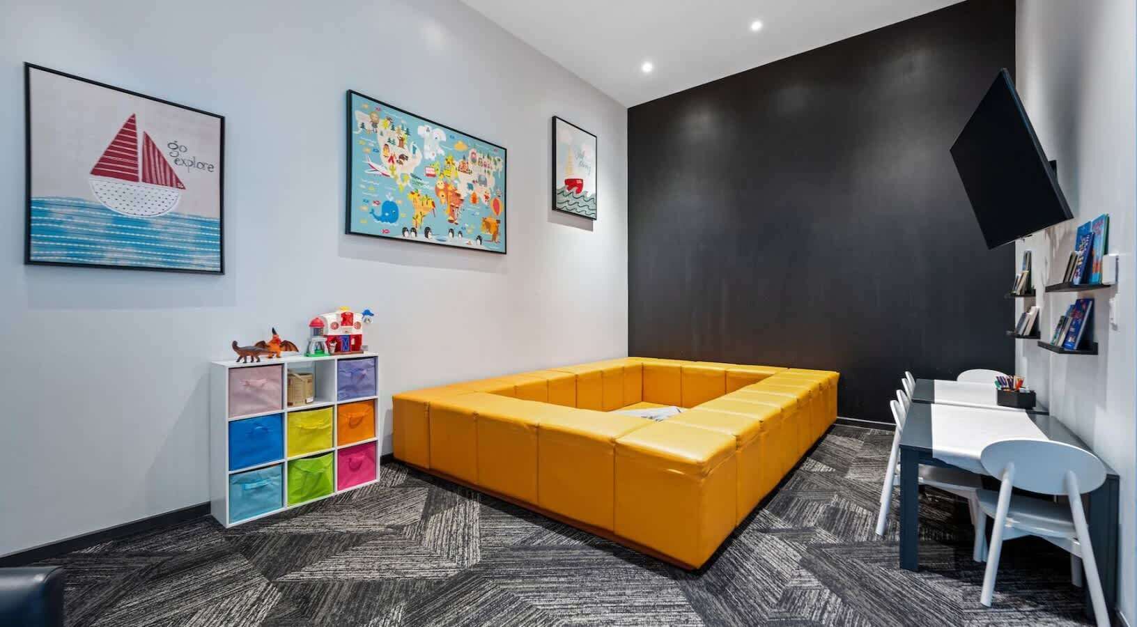 A modern room with a yellow sofa, a white desk, and a bookshelf.