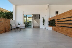 A modern interior with a wooden wall, a glass door leading to a staircase, and a seating area with chairs. - Apartment 'Casa Del Mirto' with Private Terrace, Wi-Fi and Air Conditioning (Olbia)