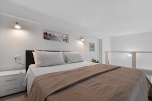 Une chambre moderne avec un lit simple, des tables de chevet et des lampes fixées au mur.