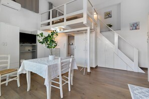 A spacious room with a dining table, chairs, a potted plant, and a staircase leading to an upper level. - Apartment 'Casa Del Mirto' with Private Terrace, Wi-Fi and Air Conditioning (Olbia)