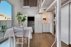 A small, well-lit room with a table, chairs, a potted plant, a television, and a wardrobe. - Apartment 'Casa Del Mirto' with Private Terrace, Wi-Fi and Air Conditioning (Olbia)