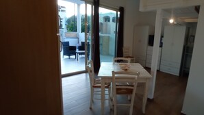 A dining area with a table and chairs, a kitchen area with cabinets, and a view through a glass door to an outdoor patio. - Apartment 'Casa Del Mirto' with Private Terrace, Wi-Fi and Air Conditioning (Olbia)