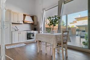 Une cuisine avec des meubles de rangement en bois, une cuisinière et une table à manger avec des chaises.