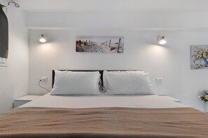 A bedroom with a bed, two bedside lamps, a painting on the wall, and a power outlet. - Apartment 'Casa Del Mirto' with Private Terrace, Wi-Fi and Air Conditioning (Olbia)