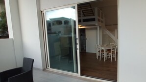 A sliding glass door leading to a balcony with a table and chairs, and a staircase to an upper level. - Apartment 'Casa Del Mirto' with Private Terrace, Wi-Fi and Air Conditioning (Olbia)