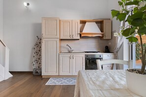 A compact kitchen with wooden cabinets, a stove, and a sink. - Apartment 'Casa Del Mirto' with Private Terrace, Wi-Fi and Air Conditioning (Olbia)