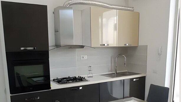 A modern kitchen with a dining area, featuring a stove, sink, and cabinets. - Apartment 'Casa Del Mirto' with Private Terrace, Wi-Fi and Air Conditioning (Olbia)