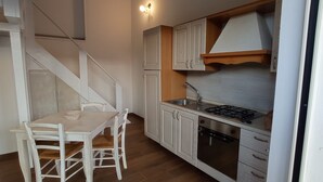 A compact kitchen with white cabinetry, a gas stove, and a sink. - Apartment 'Casa Del Mirto' with Private Terrace, Wi-Fi and Air Conditioning (Olbia)