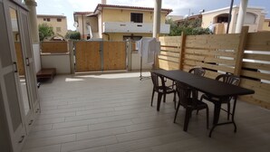 A patio with a table and chairs, a wooden fence, and a building in the background. - Apartment 'Casa Dell'Oleandro' with Private Terrace, Wi-Fi and Air Conditioning (Olbia)