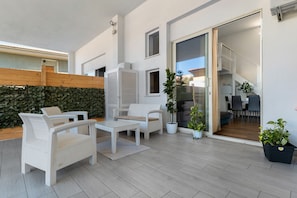 A modern outdoor patio with wicker furniture, a wooden fence, and potted plants. - Apartment 'Casa Dell'Oleandro' with Private Terrace, Wi-Fi and Air Conditioning (Olbia)