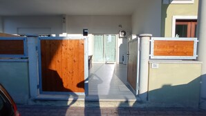 A building entrance with a wooden gate, a paved pathway, and a number '56' sign. - Apartment 'Casa Dell'Oleandro' with Private Terrace, Wi-Fi and Air Conditioning (Olbia)