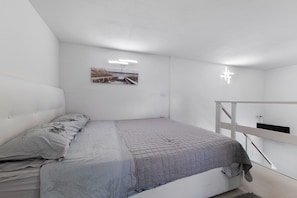 A bedroom with a bed, a headboard, a bedside table, a wall-mounted picture, and a white railing. - Apartment 'Casa Dell'Oleandro' with Private Terrace, Wi-Fi and Air Conditioning (Olbia)