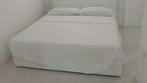 A bedroom with a bed, white walls, and a ceiling light. - Apartment 'Casa Dell'Oleandro' with Private Terrace, Wi-Fi and Air Conditioning (Olbia)