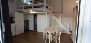 Une cuisine compacte comprenant une table et des chaises, un escalier et une petite salle de bain.