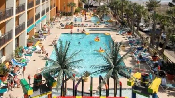 A hotel pool area with multiple levels of balconies, a central pool, and a beach view. - Cozy 1-bedroom condo in tranquil Myrtle Beach (Myrtle Beach)
