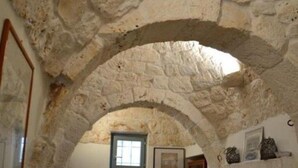A stone-walled room with a sofa, a small table, and a fireplace.